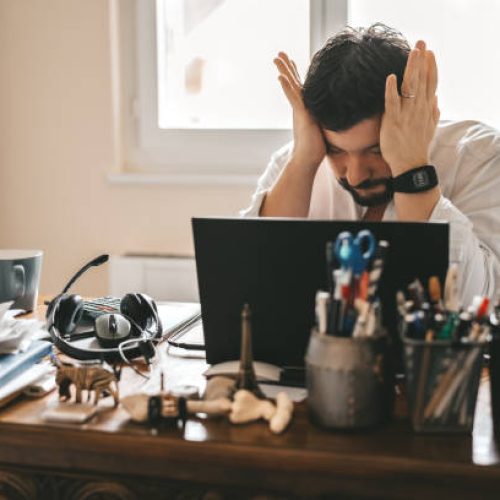 Tired frustrated exhausted businessman working from home online sitting at home office with laptop during quarantine and self isolation period at pandemic. Crisis management. Despair of market falling down.